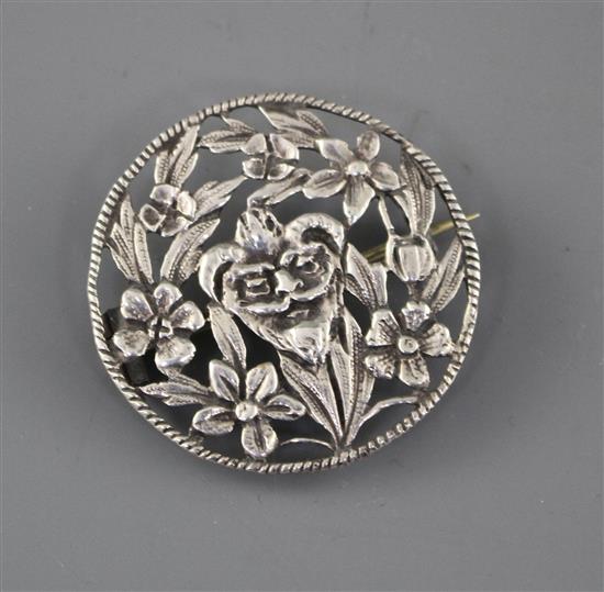 A late Victorian pierced white metal brooch, decorated with central mask amid foliage,